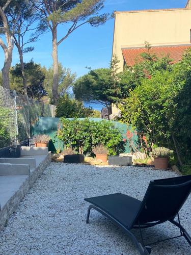 une chaise noire assise au milieu d'un jardin dans l'établissement Logement entier T2 climatisé, parking gratuit, jardin, plage à 2min à pied, à Sanary-sur-Mer