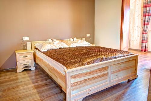 a large bed in a bedroom with a wooden floor at Noclegi Styrnol & SPA in Zawoja