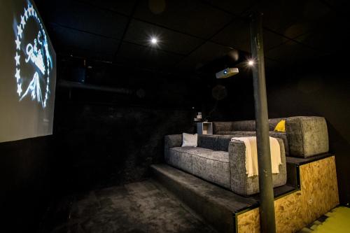 a couch in a dark room with a tv at Gite Villa Avril piscine- jacuzzi- sauna - 15 Pers-proche Europapark in Sélestat
