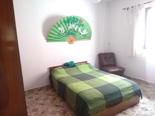 un dormitorio con una cama y una silla en Casa Centro de Peruíbe - R&P, en Peruíbe