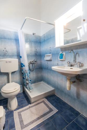 a blue tiled bathroom with a toilet and a sink at Vlassis Studios in Mesongi