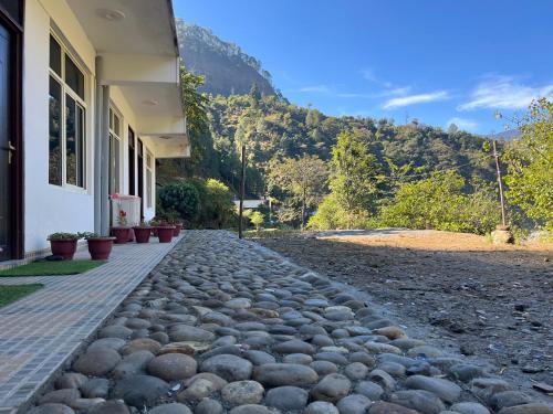 a stone path next to a house with a mountain at River Valley in Chamoli
