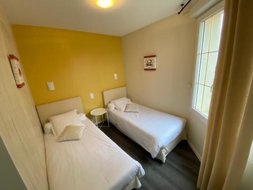 two beds in a room with yellow walls at Hôtel de charme & SPA Le Grand Large in La Bernerie-en-Retz