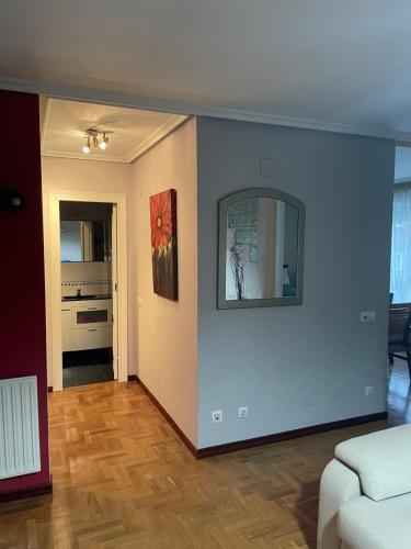 sala de estar con sofá y espejo en la pared en Apartamento Parque del Oeste en Oviedo