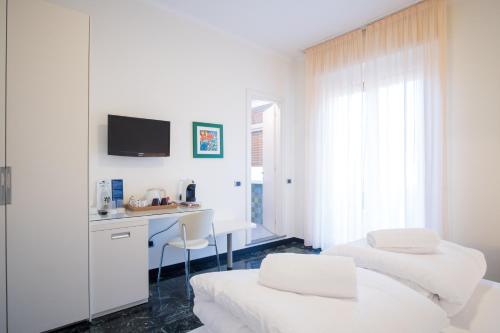 a white room with two beds and a desk at Hotel Garden in Levanto