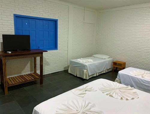 a room with two beds and a table with a television at Pousada Barra Bonita in Bonito