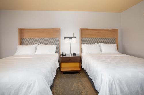 two beds in a hotel room with white sheets at Holiday Inn Winchester Southeast-Historic Gateway by IHG in Winchester