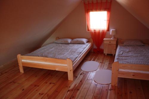 sypialnia z 2 łóżkami, oknem i drewnianą podłogą w obiekcie Oaza Spokoju w Łokciowych