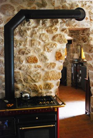 a stone kitchen with a stove and a stone wall at B&B Casal Cominium in San Donato Val di Comino