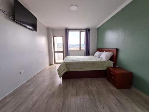 een slaapkamer met een bed en een groot raam bij Hostal Morlaquita in Cuenca