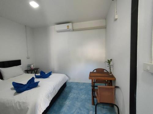 Seahorse Lipe Hostel في كو ليبي: غرفة مع سرير ووسائد زرقاء ومكتب