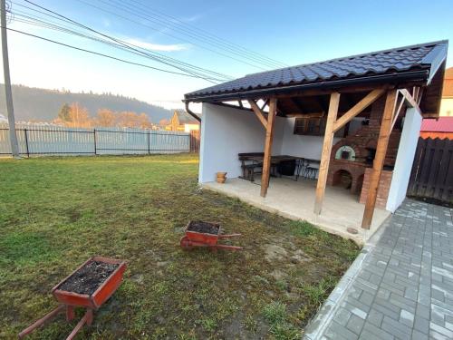 a shed with a table and a grill in a yard at Casa Mocanu in Sărmaş