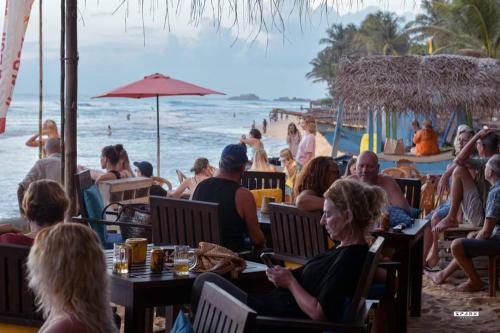 a group of people sitting at a beach restaurant at Sunnyplace Guest Mirissa in Mirissa
