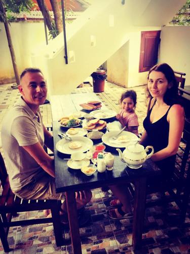 a man and woman sitting at a table with a child at Sunnyplace Guest Mirissa in Mirissa