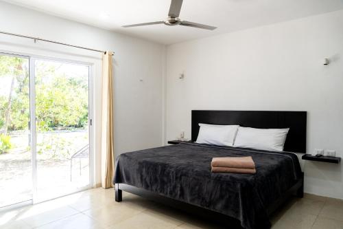 1 dormitorio con 1 cama y puerta corredera de cristal en Hotel Casa Tortuga Tulum - Cenotes Park Inclusive, en Tulum