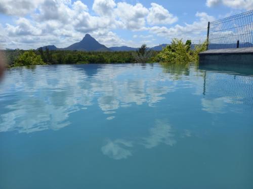 a pool of water with a mountain in the background at 373 Wolmar Cosy and Modern Apartment- 200 metres from the Beach and Supermarkets and just next to Domaine de wolmar with views of deers and green natural park in Flic-en-Flac