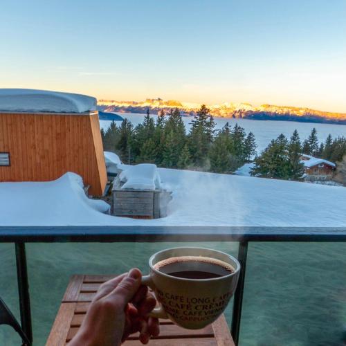a person holding a cup of coffee on a balcony at L'écrin du Vernon in Chamrousse