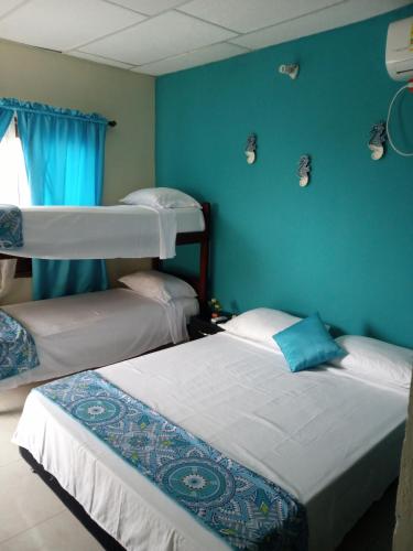 two beds in a room with blue walls at AquaMarina Hostal in Tolú