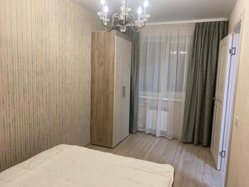 a bedroom with a bed and a chandelier at Уютные апартаменты на Трехсвятской in Tver