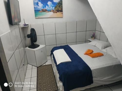 a small bedroom with a bed with a phone on it at Pousada Praia Grande Solemar in Praia Grande