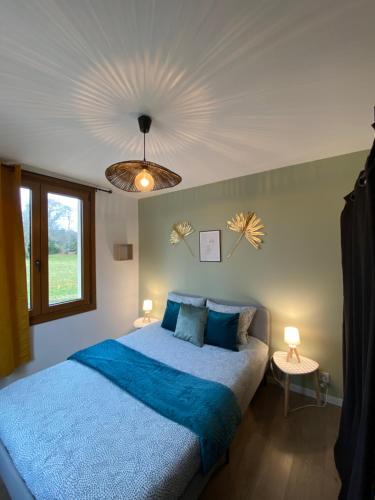 Schlafzimmer mit einem Bett mit blauer Bettwäsche und einer Decke in der Unterkunft appartement au coeur de Loupiac in Loupiac-de-Cadillac