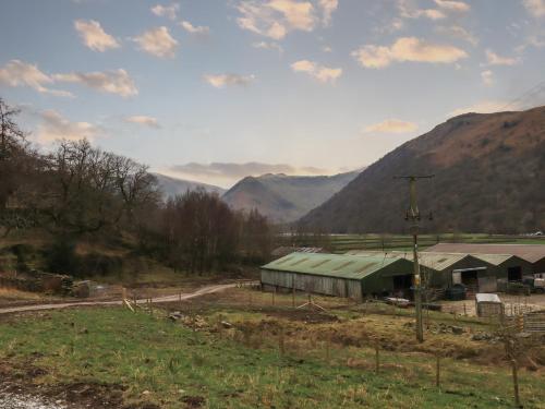 a barn in a field with mountains in the background at Jenny - Crossgate Luxury Glamping in Penrith