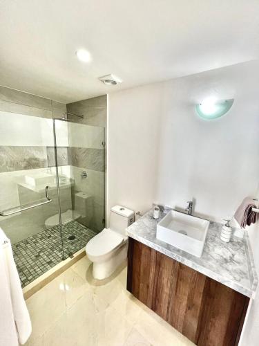 a bathroom with a toilet and a sink and a shower at Sunset View Malecón 1402 Vista panoramica al mar in Mazatlán