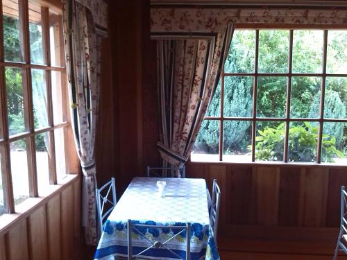 a table and chairs in a room with windows at Hostal Kutralwe in Pucón