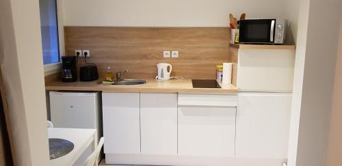 a small kitchen with white cabinets and a microwave at ty-yan in Tours