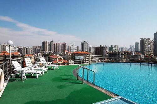 a balcony with a pool and chairs and a city skyline at Guangdong Victory Hotel- Located on Shamian Island in Guangzhou