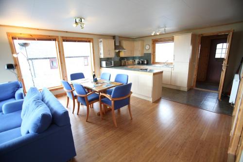 a living room with a blue couch and a table and chairs at Buxa Farm Chalets in Orphir