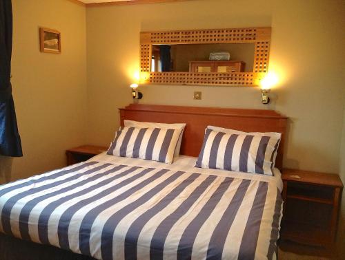 a bedroom with a bed with two pillows and a mirror at Buxa Farm Chalets in Orphir