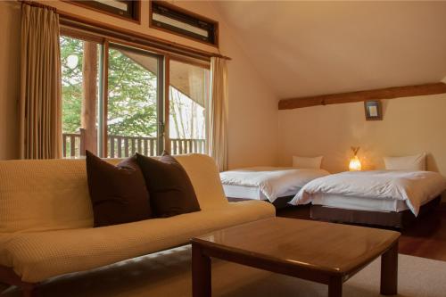 sala de estar con 2 camas y sofá en Lodge Denbey, en Nozawa Onsen