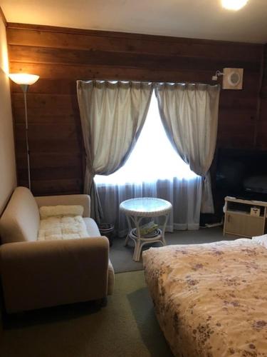 1 dormitorio con cama, sofá y ventana en Yamagata Zao Pension Aplon Stage, en Kaminoyama