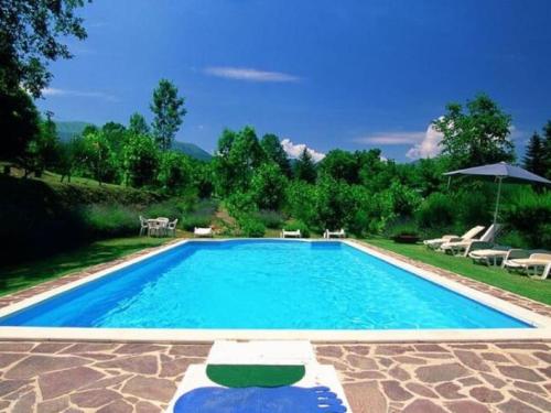 a large swimming pool with chairs and an umbrella at Belvilla by OYO Terrazze in Amandola