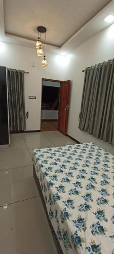 a bedroom with a bed with a blue and white comforter at Telma Beach Homestay in Mararikulam
