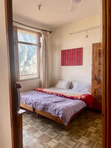 a bedroom with a bed and a window at Sarthak Home Stay, Beautiful Valley view of Mountain in Jagatsukh