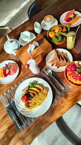 a wooden table with plates of food on it at Eaze Villas Uluwatu in Uluwatu