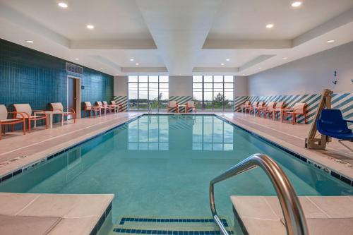 uma grande piscina com cadeiras e mesas num edifício em Holiday Inn - Erie, an IHG Hotel em Erie