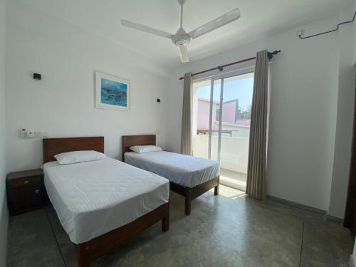 ein Schlafzimmer mit zwei Betten und einem großen Fenster in der Unterkunft Kalan Mirissa in Mirissa