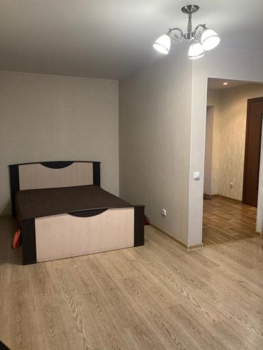 um quarto com uma cama num quarto com pisos em madeira em Апартаменты у вокзала em Kirov