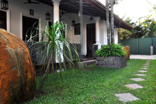 a house with a yard with grass and plants at Mama Villa Hikkaduwa in Hikkaduwa