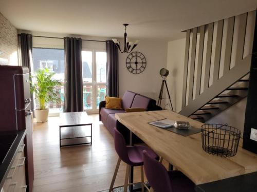 a living room with a couch and a dining room table at Appartement neuf style industriel *** proche de la mer in Roscoff