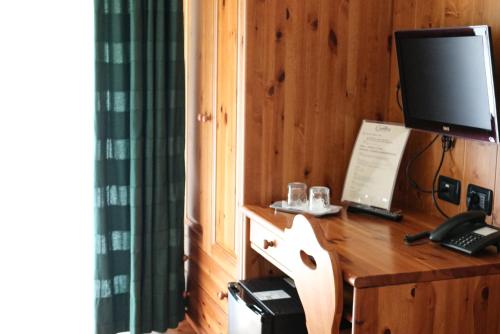 a room with a desk with a television and a telephone at Hotel Garni Civetta in Selva di Cadore