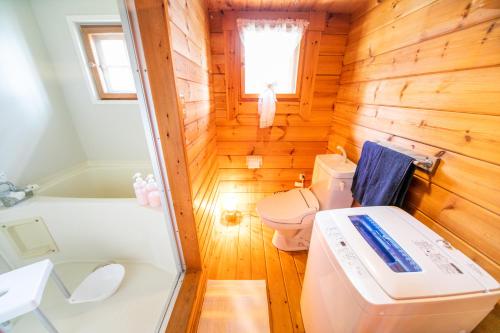a wooden bathroom with a toilet and a bath tub at Awaji Seaside Log house in Goshiki 1 in Sumoto