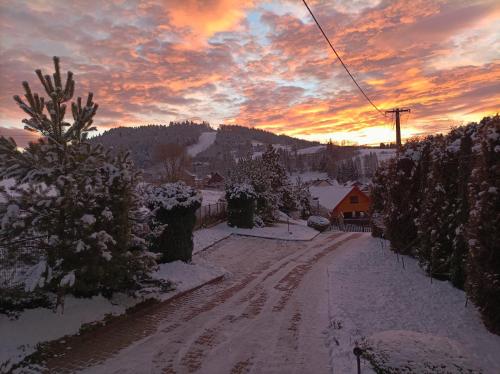 a snow covered street with a sunset in the background at Dom Sosenek in Kluszkowce