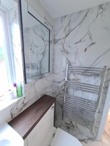 a bathroom with a toilet and a marble wall at Umbrella Properties London Excel in London