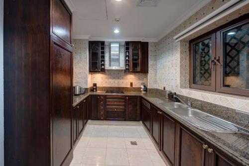 a large kitchen with wooden cabinets and a sink at Durrani Homes - Persian Luxury at Souk Al Bahar with Private Jaccuzi in Dubai