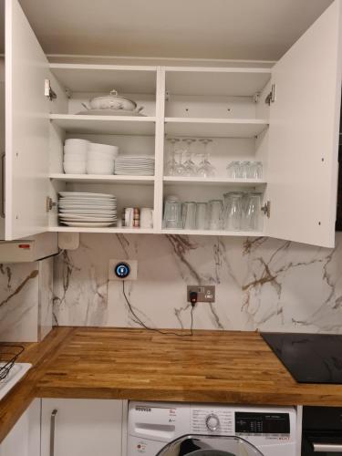 a kitchen with white cabinets and a counter with dishes at Umbrella Properties London Excel in London