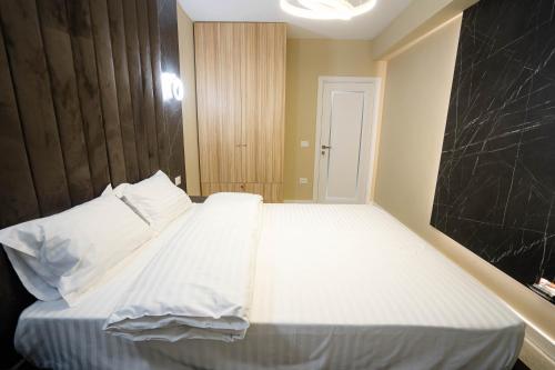 a bedroom with a large bed with white sheets at Deluxe Aparthotel MARWELL RESIDENCE in Suceava